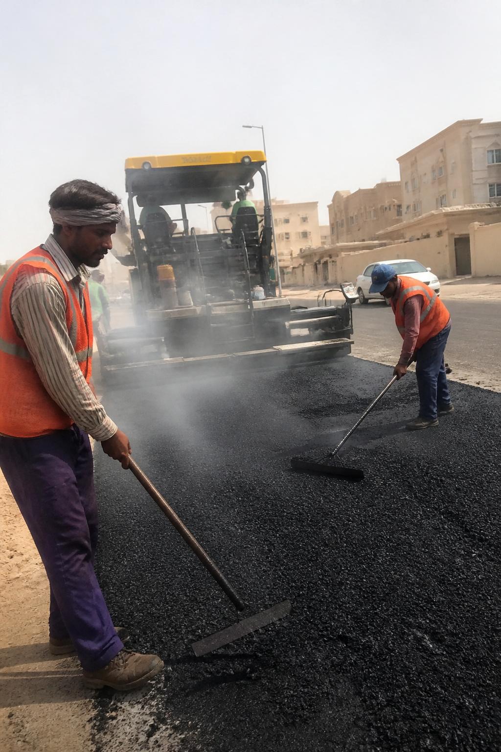 عمال السفلتة يفردون الإسفلت الحار في شارع بجدة